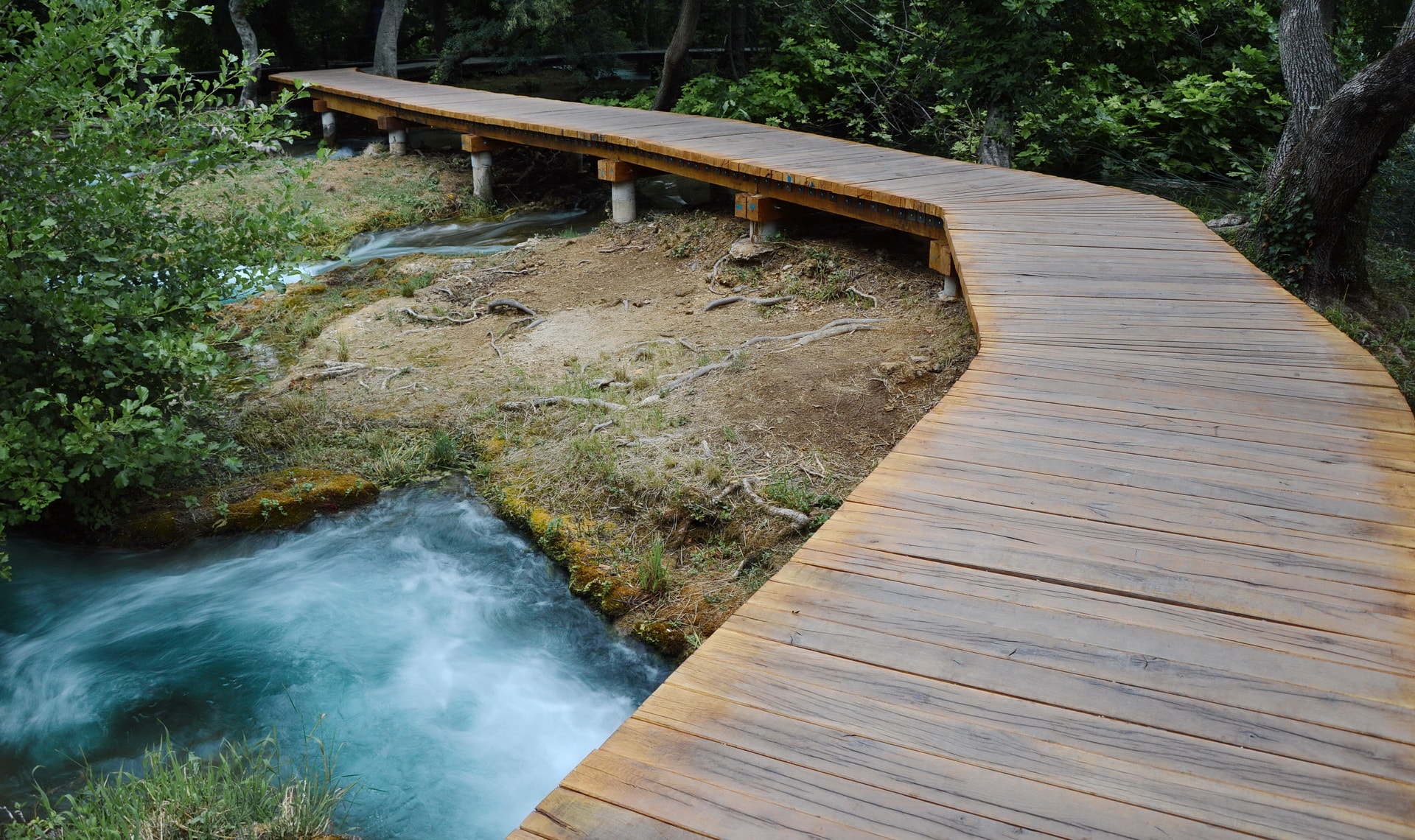 Dark blue water streams underneath the wooden bridges